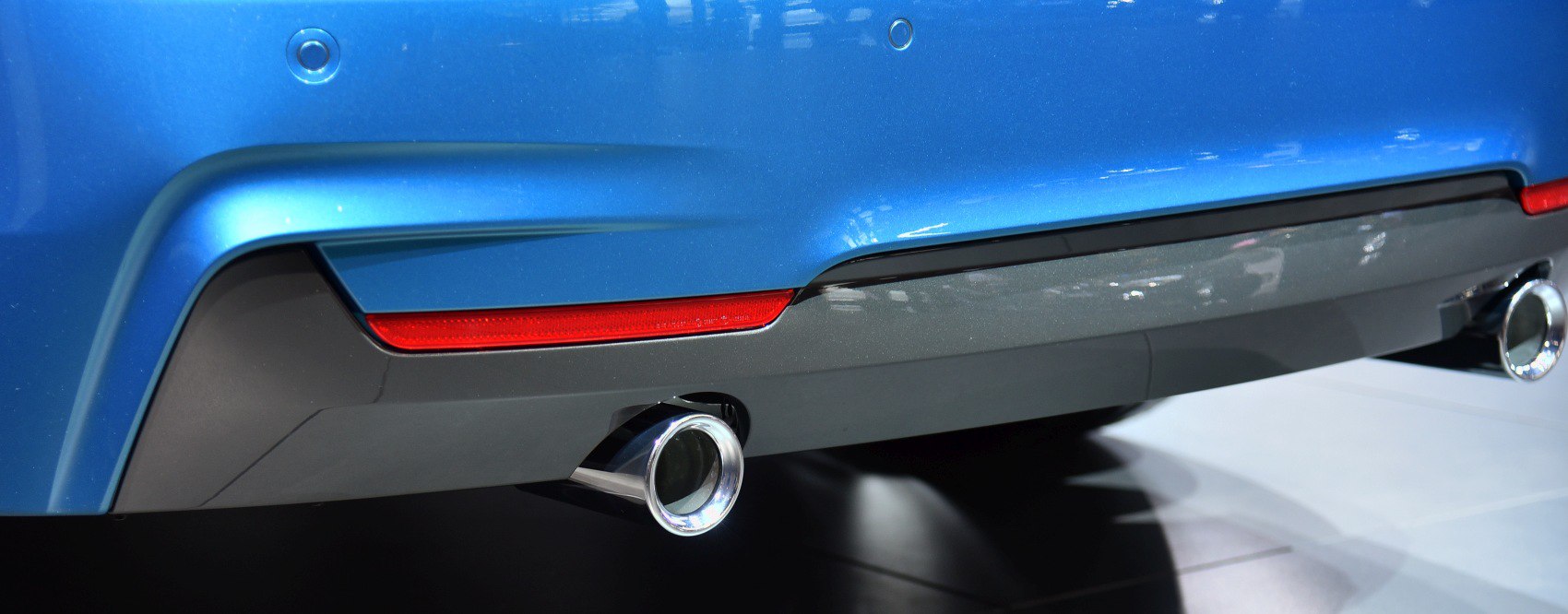 Rear dual exhaust tips and reflector on blue bumper