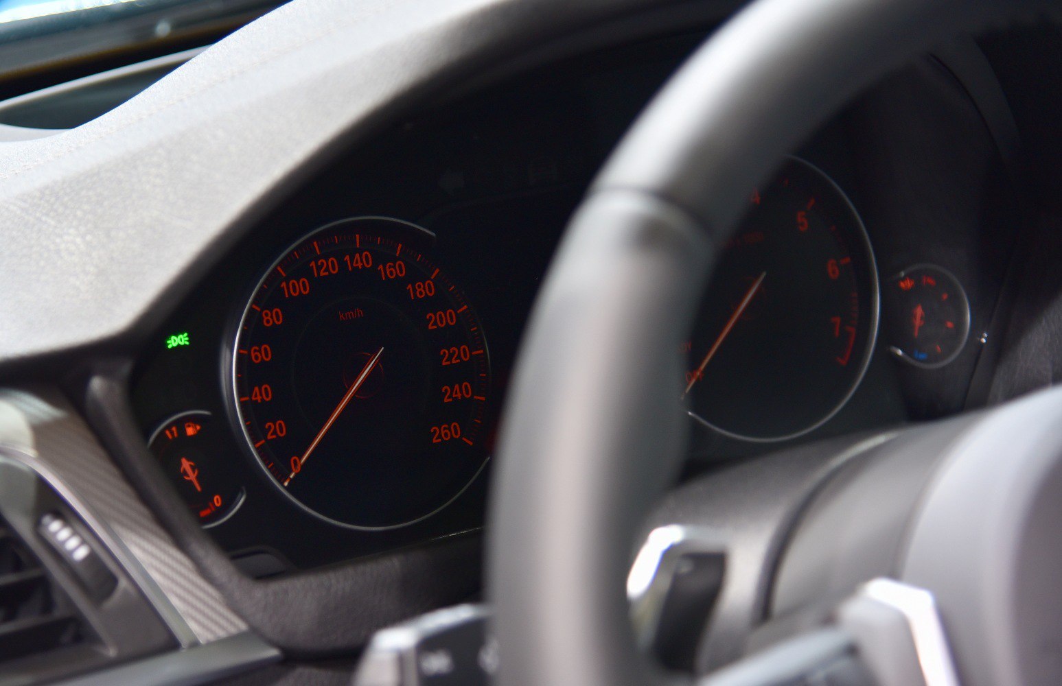 Analog instrument cluster with speedometer and tachometer illuminated in red