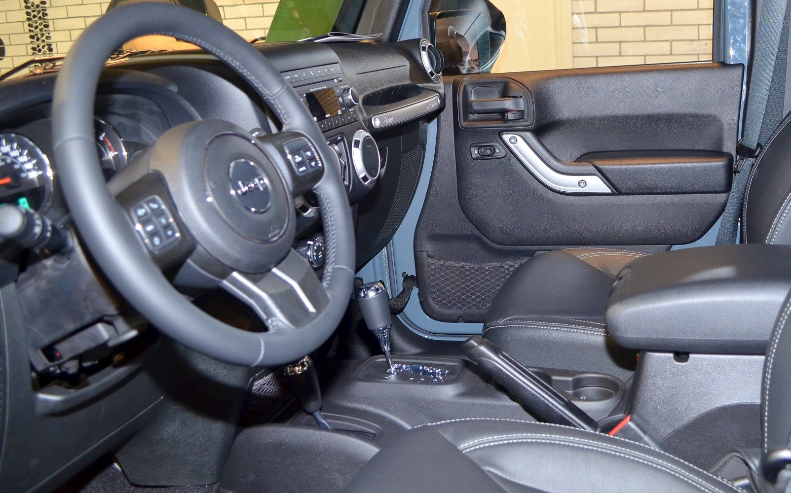 Car interior with steering wheel, dashboard, and gear shift.