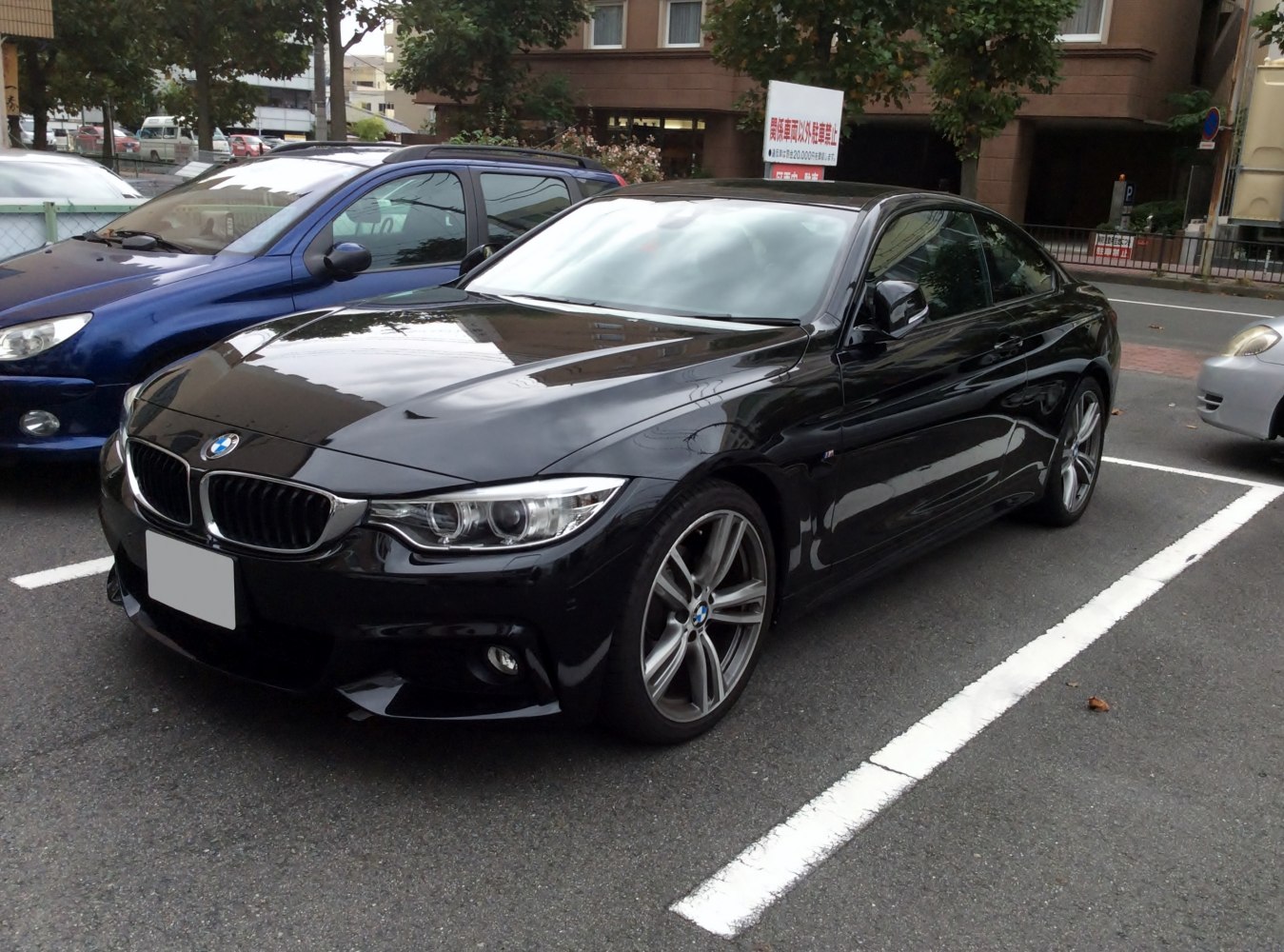 High-angle front-side view, sharp headlights, kidney grille, black coupe