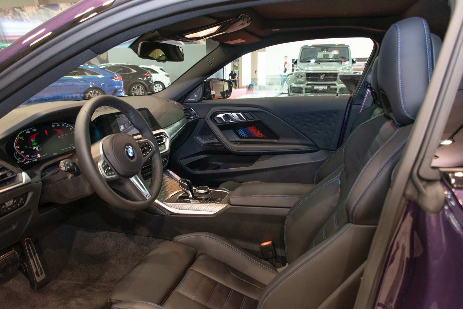 Car interior showing steering wheel, digital dashboard, and leather seats