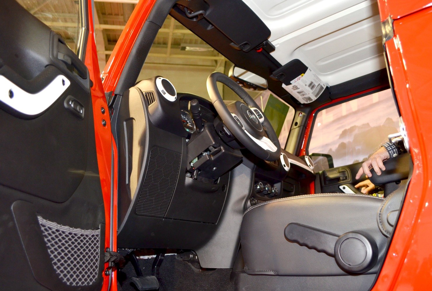 Dashboard and steering wheel interior with manual seat adjuster and door mesh pocket