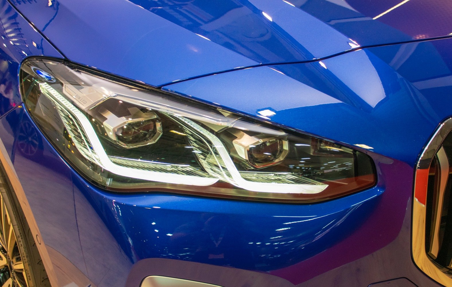 Close-up of a modern LED car headlight on a blue body