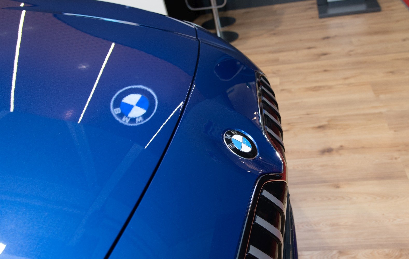Blue car front hood with kidney grille and BMW emblem reflection