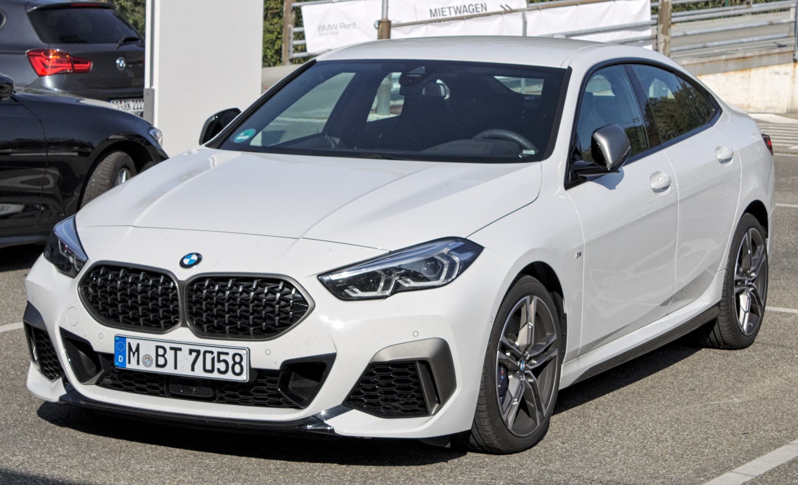 Front view of a sporty white sedan with LED headlights and kidney grille