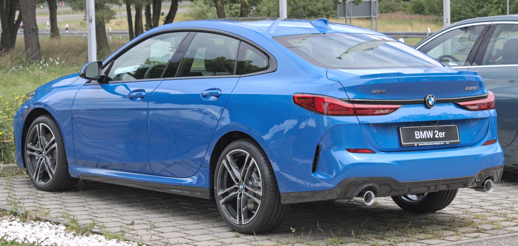 Rear and side view of a sleek blue sporty sedan with dual exhausts