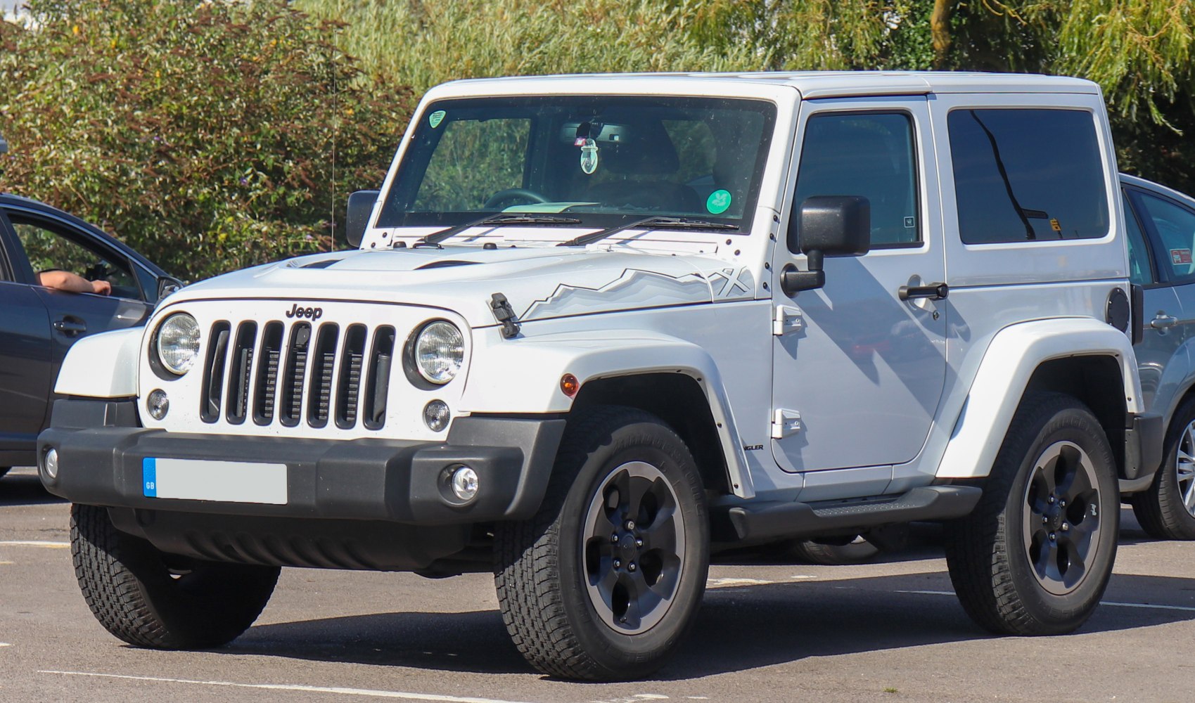 White off-road SUV with seven-slot grille, round headlights, mountain hood decal