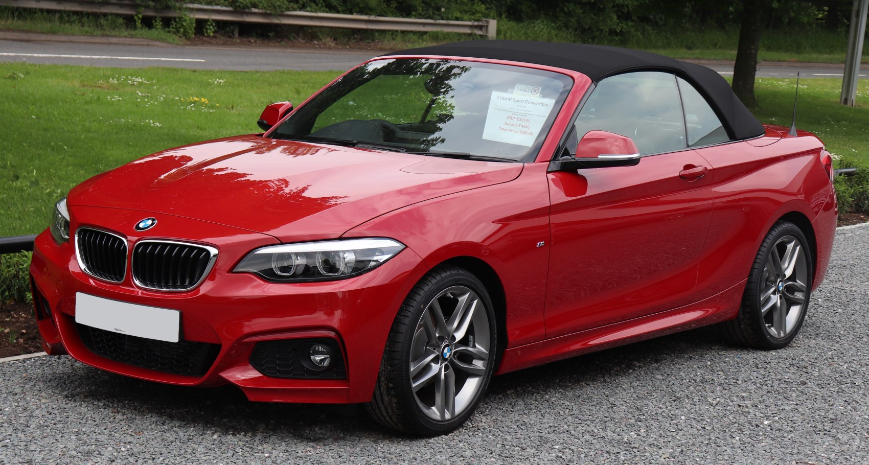 Red convertible with black soft top and alloy wheels, front side view