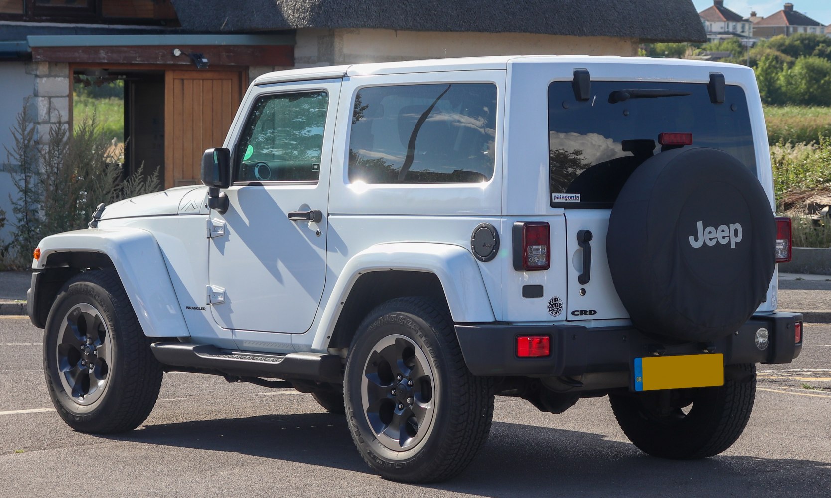 White two-door SUV with spare tire cover and black rims rear side view