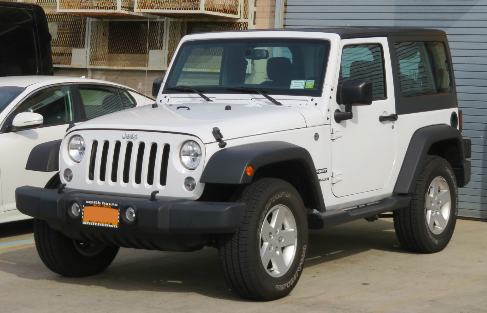 White two-door SUV with classic Jeep grille and round headlights