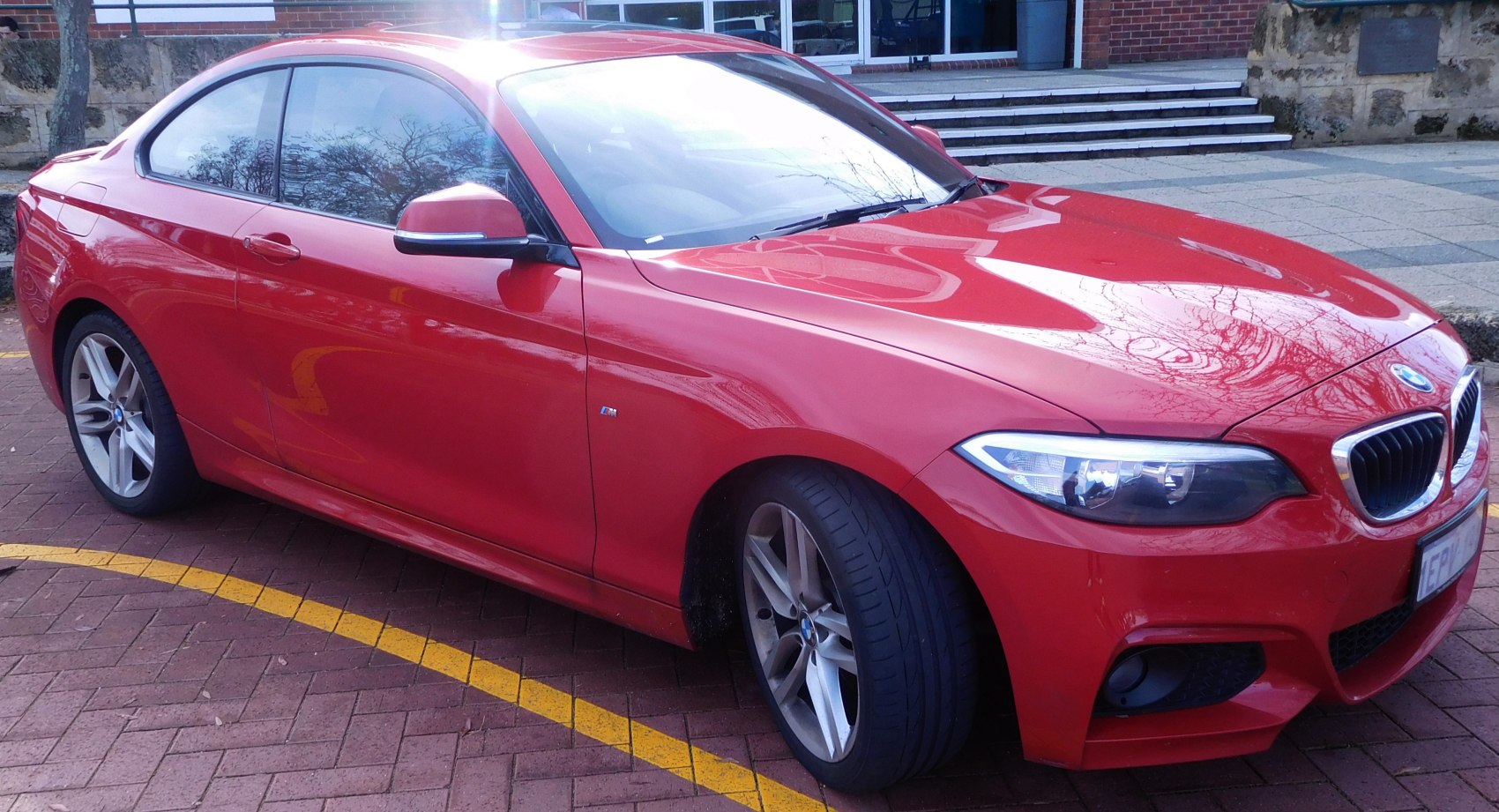 Red coupe with sporty alloy wheels and aerodynamic M Sport body kit