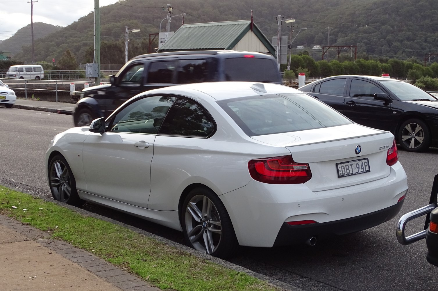 Rear side view of white coupe with distinctive taillights and sleek profile.