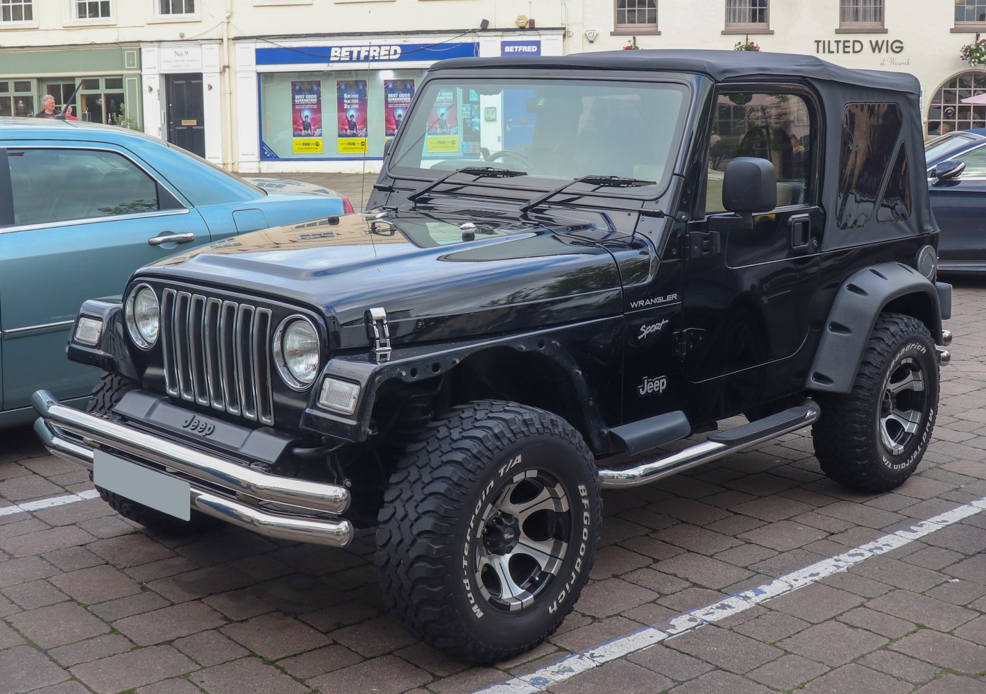 Black Jeep Wrangler II with soft top and rugged off-road tires