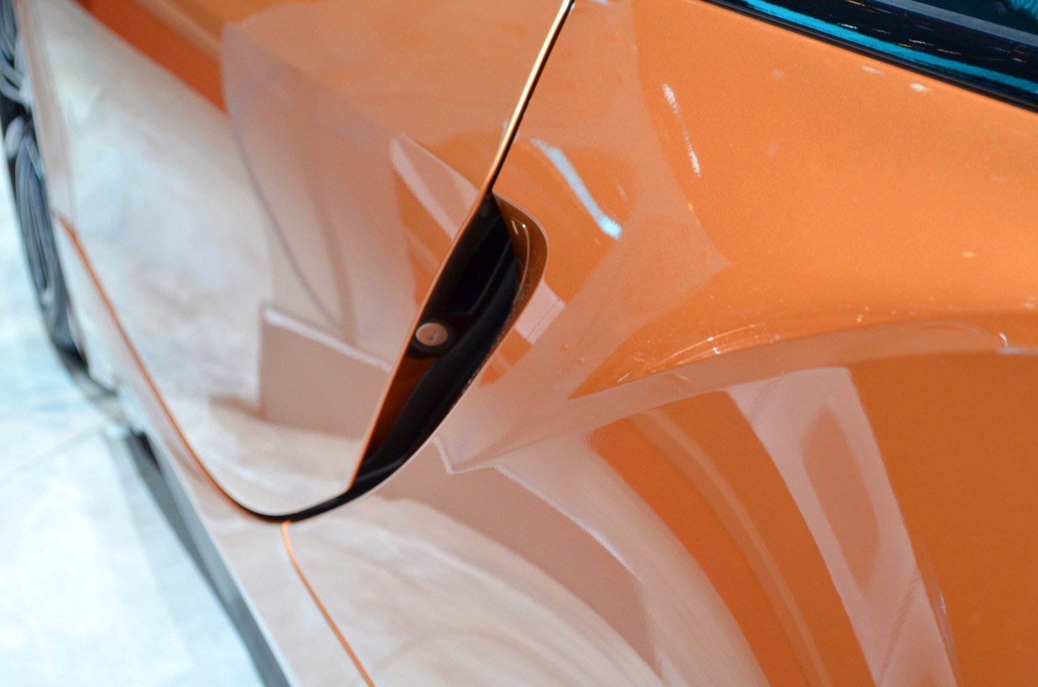Close-up of door handle and side body line in metallic orange
