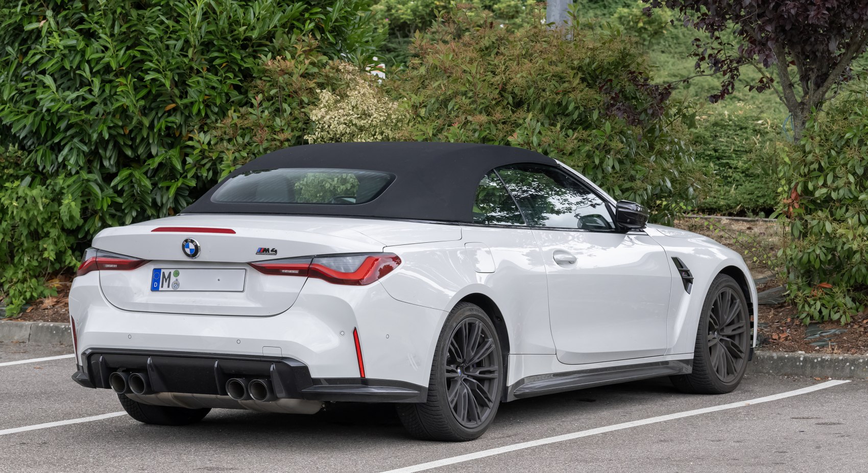 Rear-side view of a convertible with soft top and quad exhaust pipes