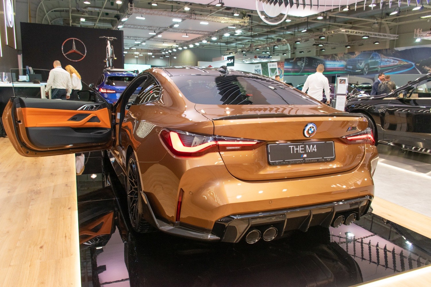 Rear view of a sports coupe with open door and quad exhaust pipes