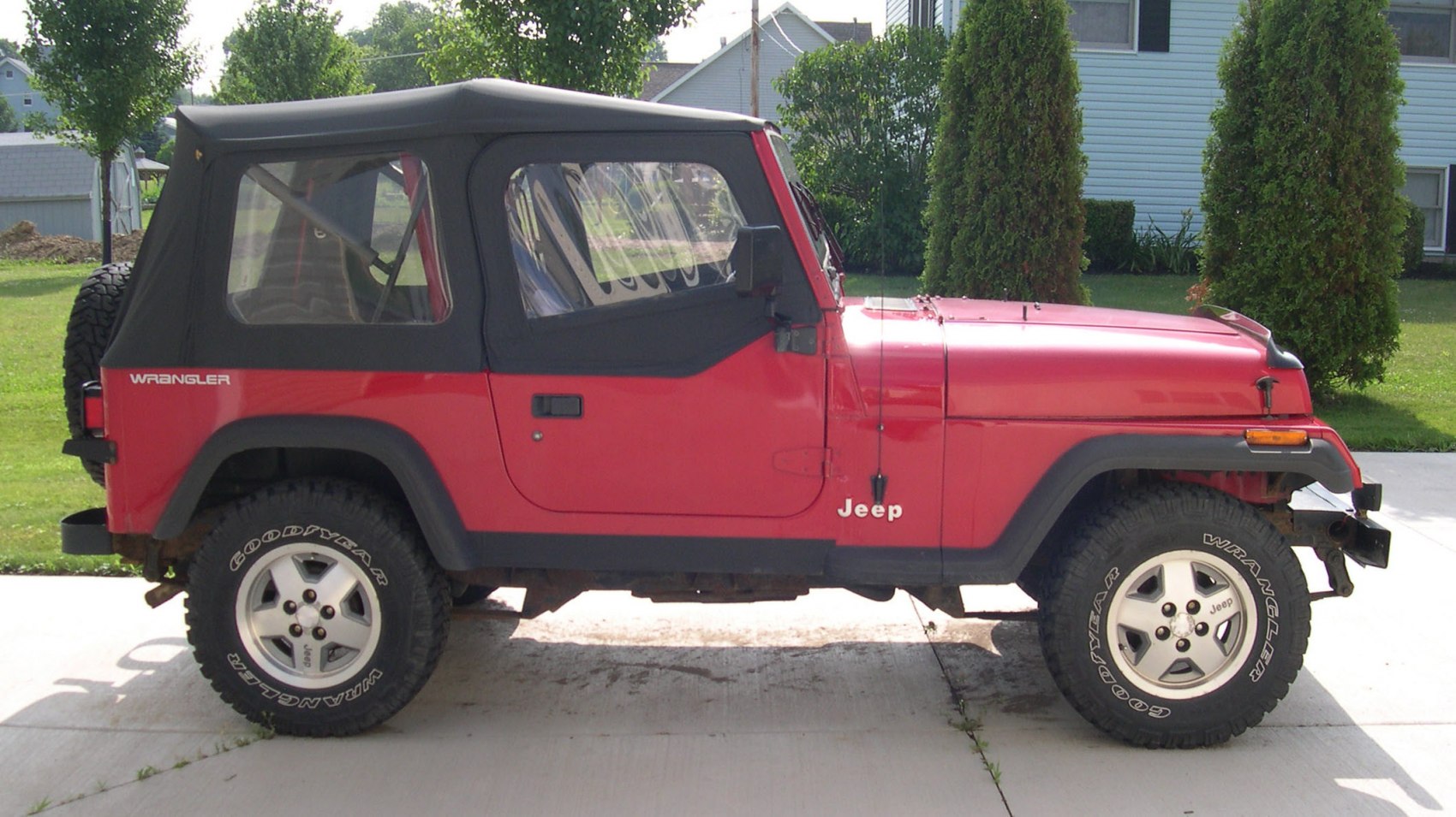 Side view of red Jeep with soft top and off-road tires