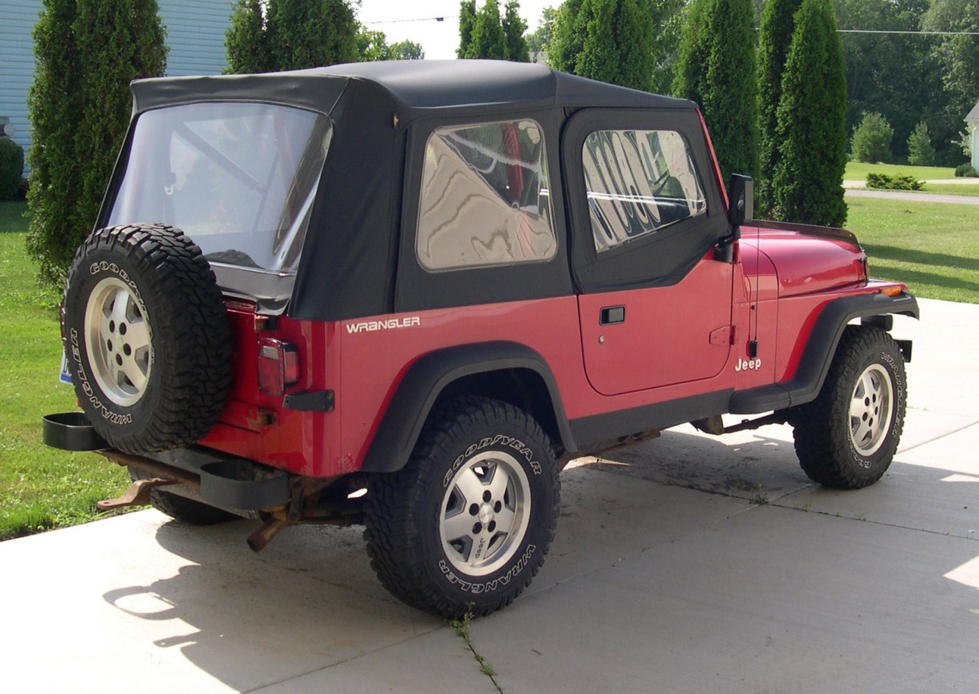 Red Jeep with black soft top and rear spare tire