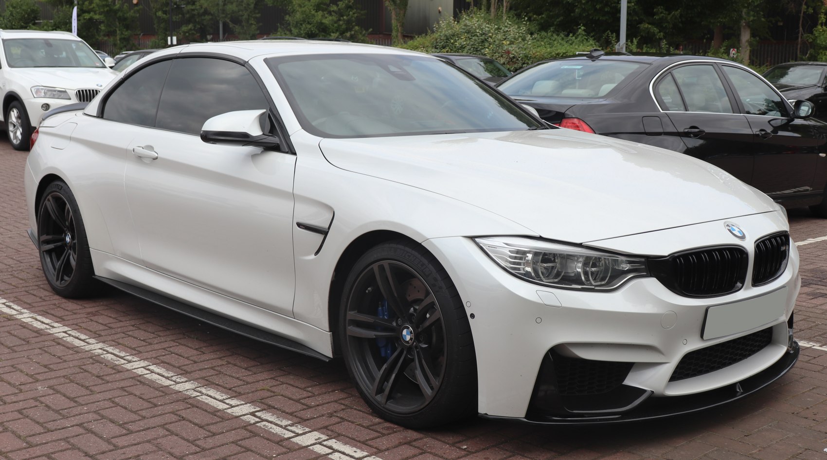 Front side view of white sporty coupe with black wheels.