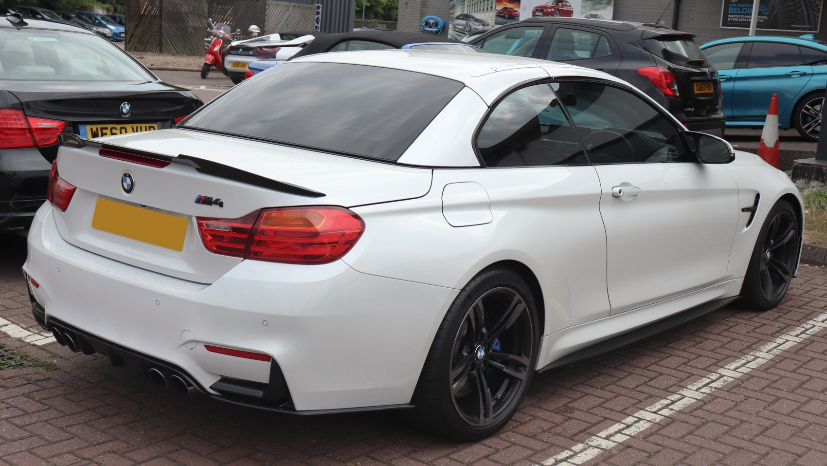 Rear and side view of white convertible with black wheels and spoiler