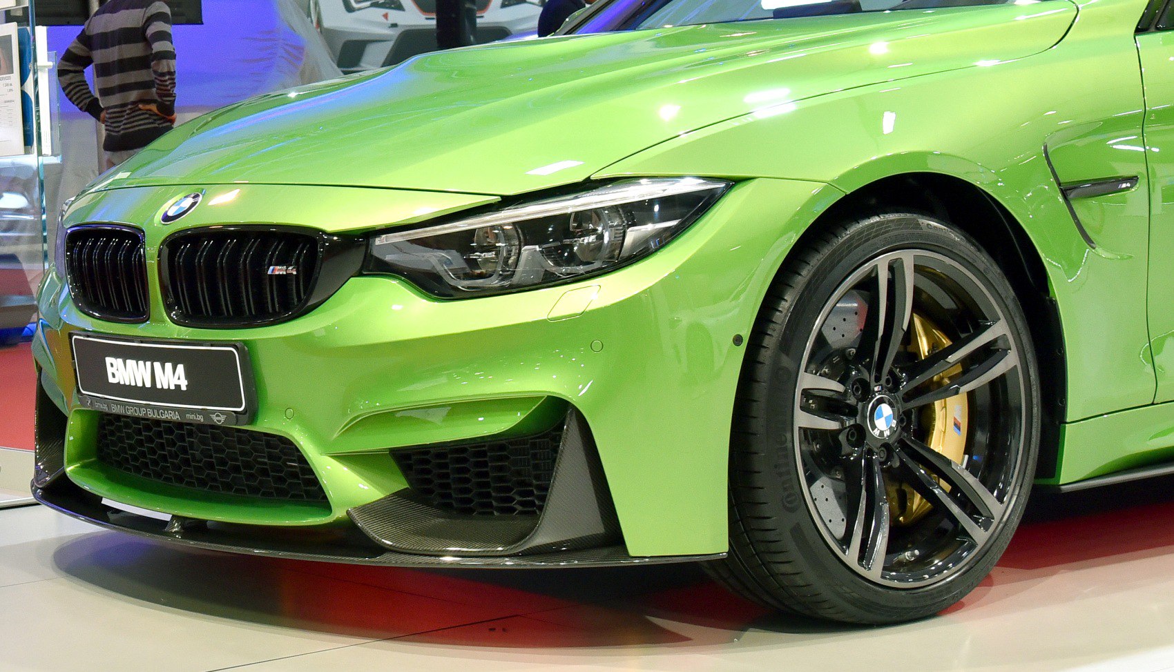 Close-up of front wheel, rim, brake disc, and sporty bumper of a bright green car