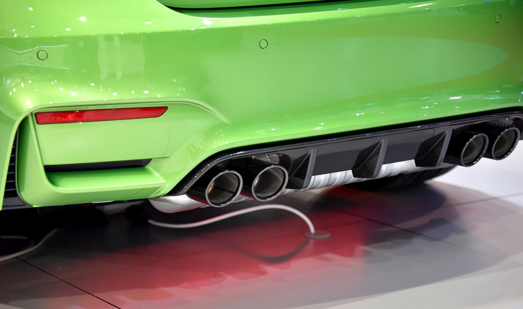Quad exhaust tips and carbon fiber rear diffuser on car's green rear bumper