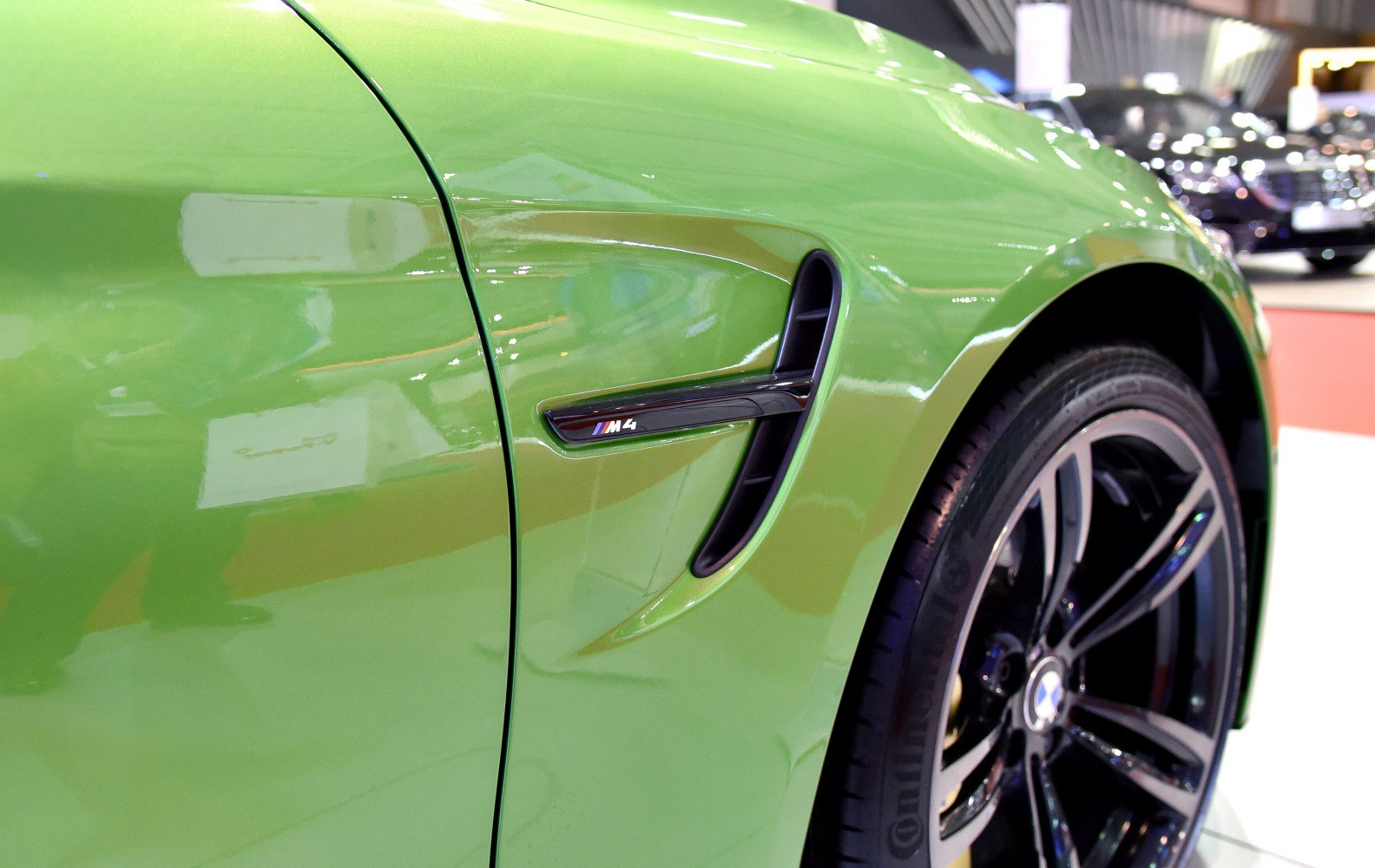 Close-up of side vent with M4 badge and front wheel with alloy rim.