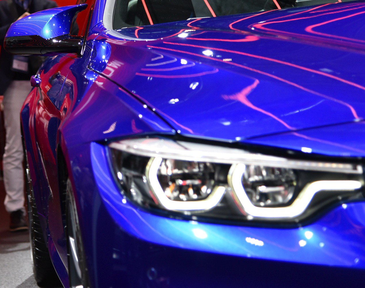Close-up of blue car's front headlight and side mirror.