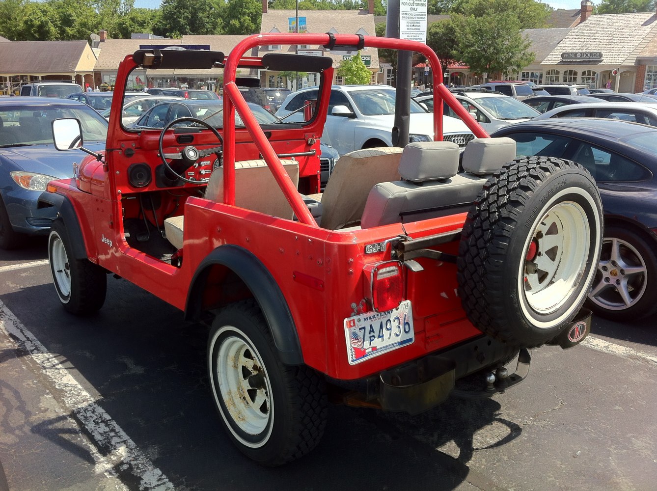 Red Jeep with open roof, roll bar, and rear spare tire