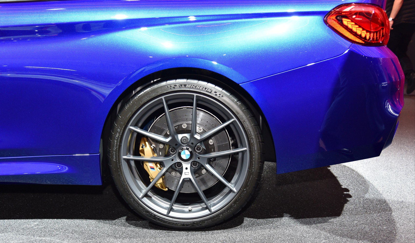 Close-up of a multi-spoke alloy wheel with gold brake caliper and large drilled disc.