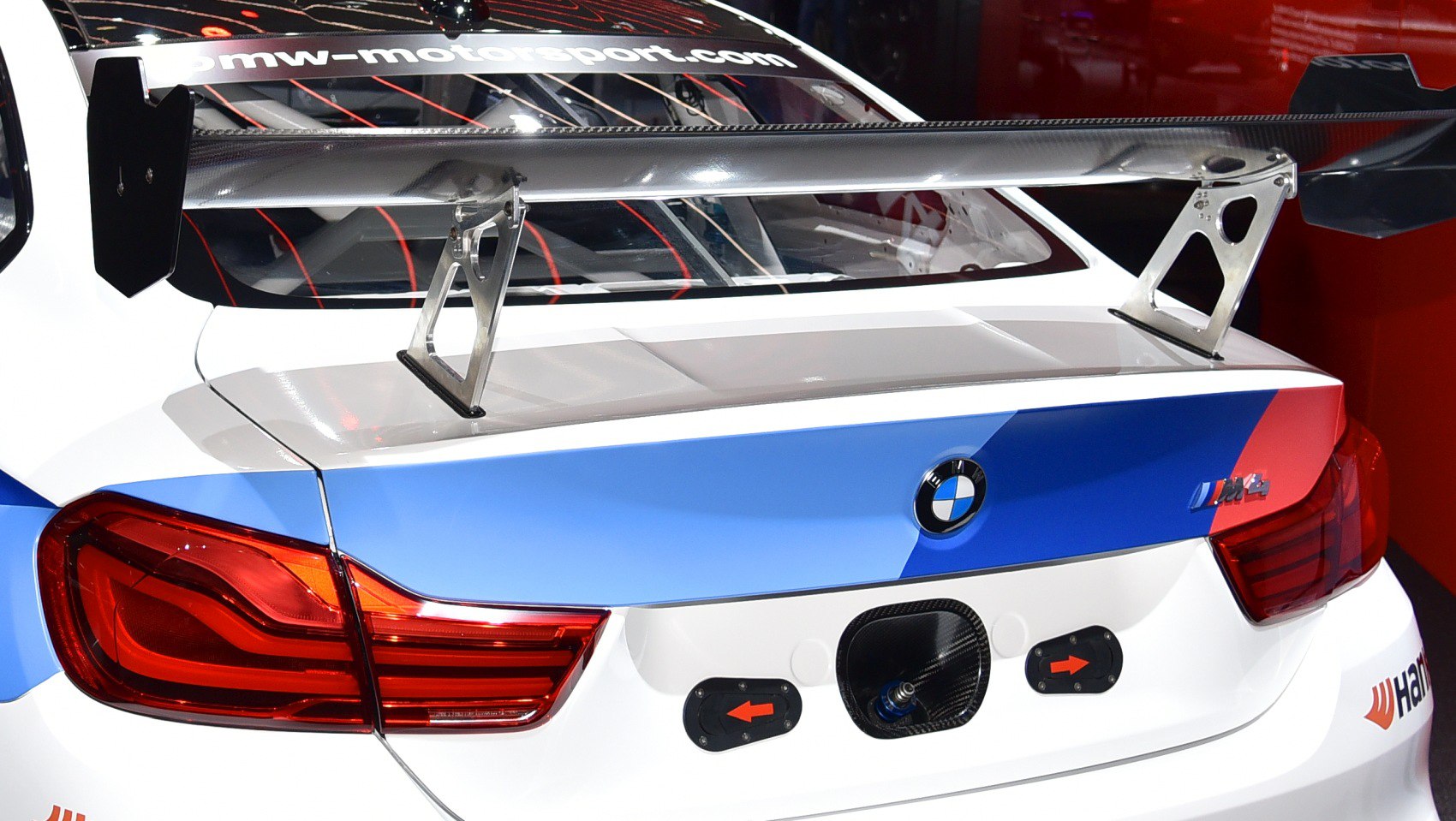 Racing spoiler and motorsport livery on car rear with vivid tail lights