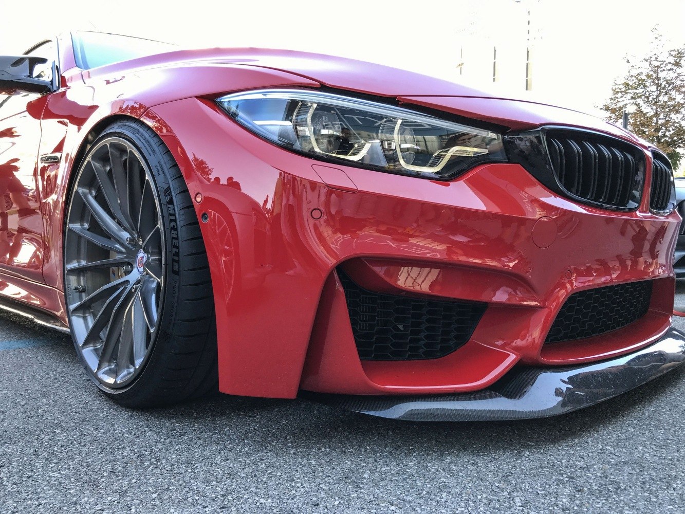 Close-up of red car front with headlight and multi-spoke alloy wheel