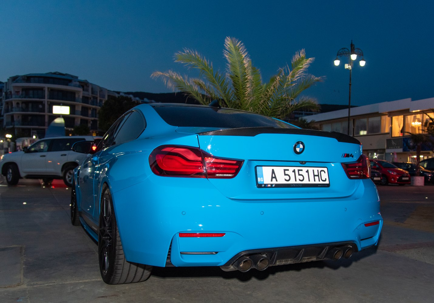 Rear view showing quad exhaust and tail lights on a blue sports coupe
