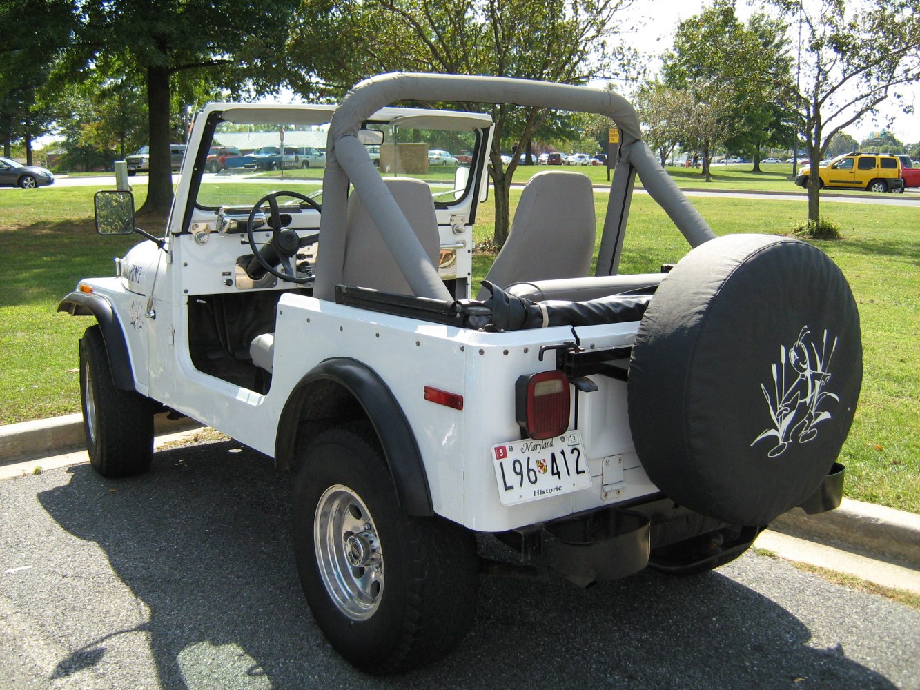 Open-top off-road vehicle with exposed roll bar and rear spare tire cover