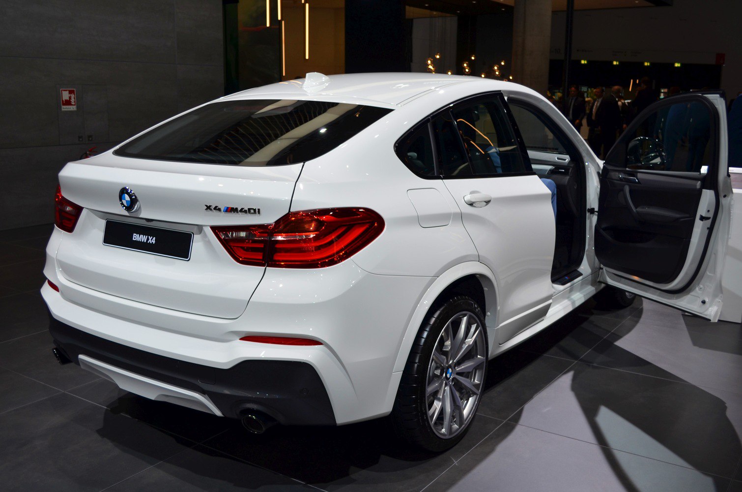 Rear side view of a white SUV with open door and modern taillights
