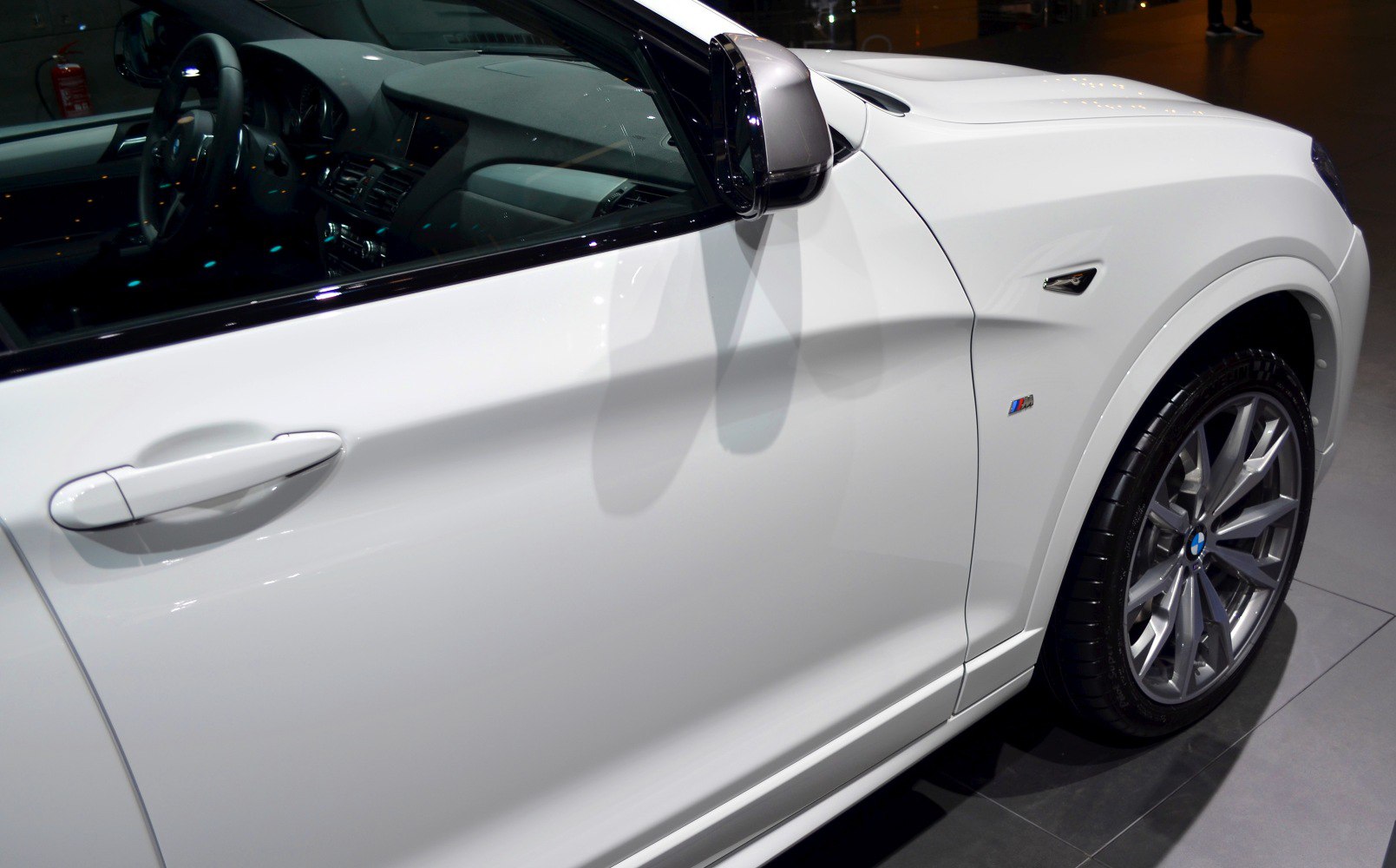 White SUV side door, side mirror, M badge, and alloy wheel close-up