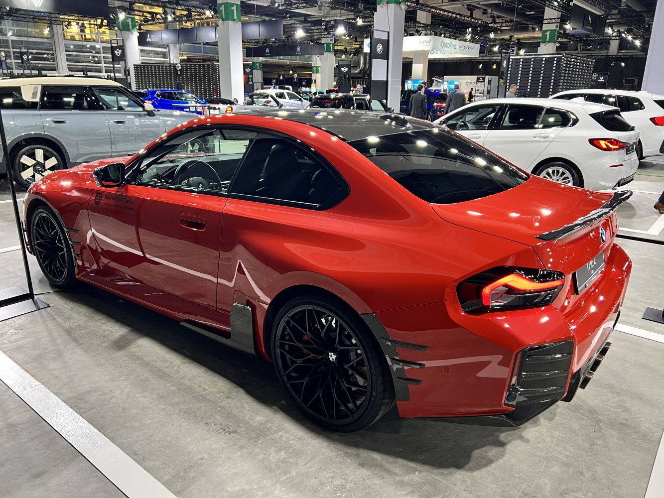 Red coupe with carbon fiber roof, aerodynamic wing, and black multi-spoke wheels