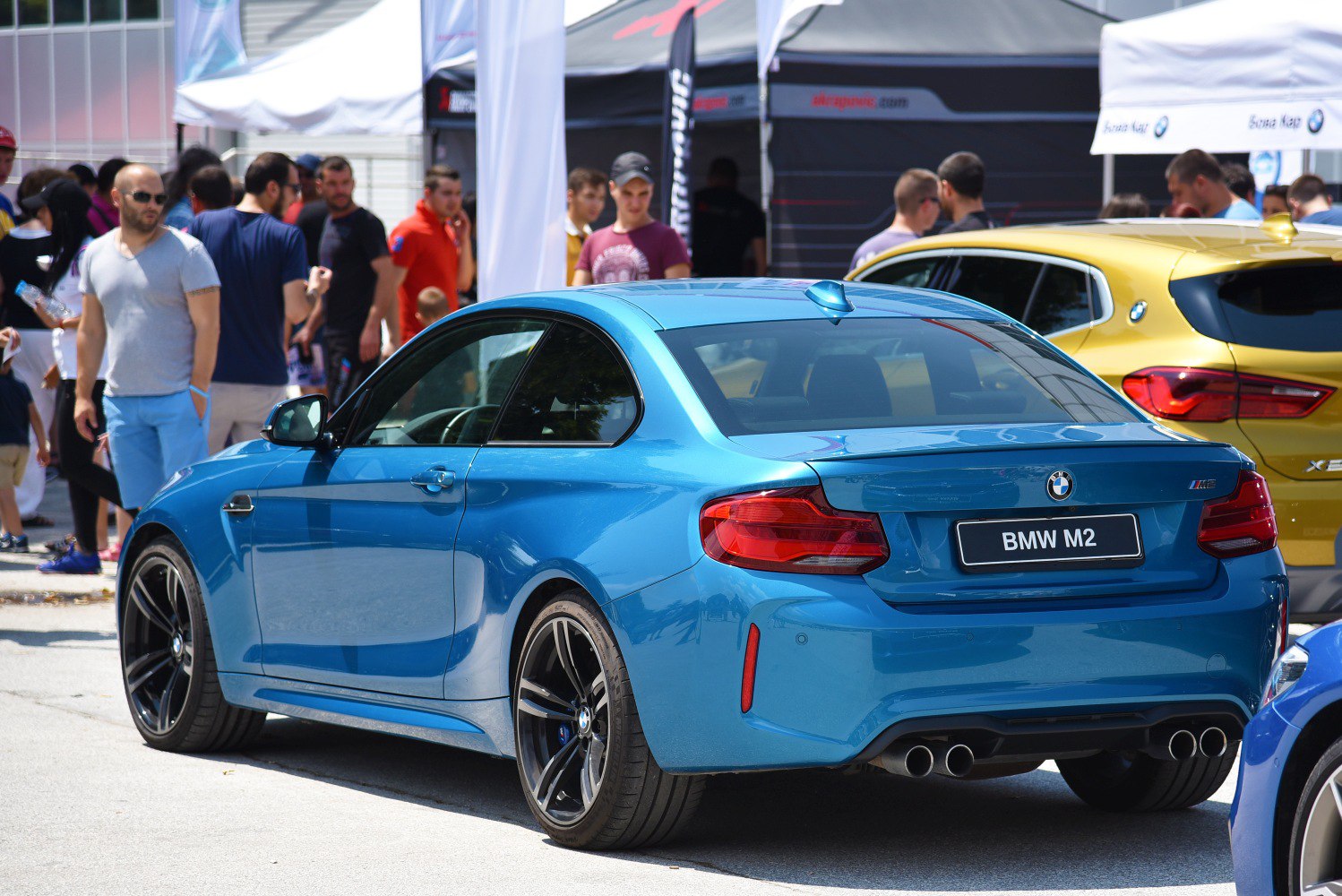 Rear-side blue sports coupe with quad exhaust and black alloy wheels
