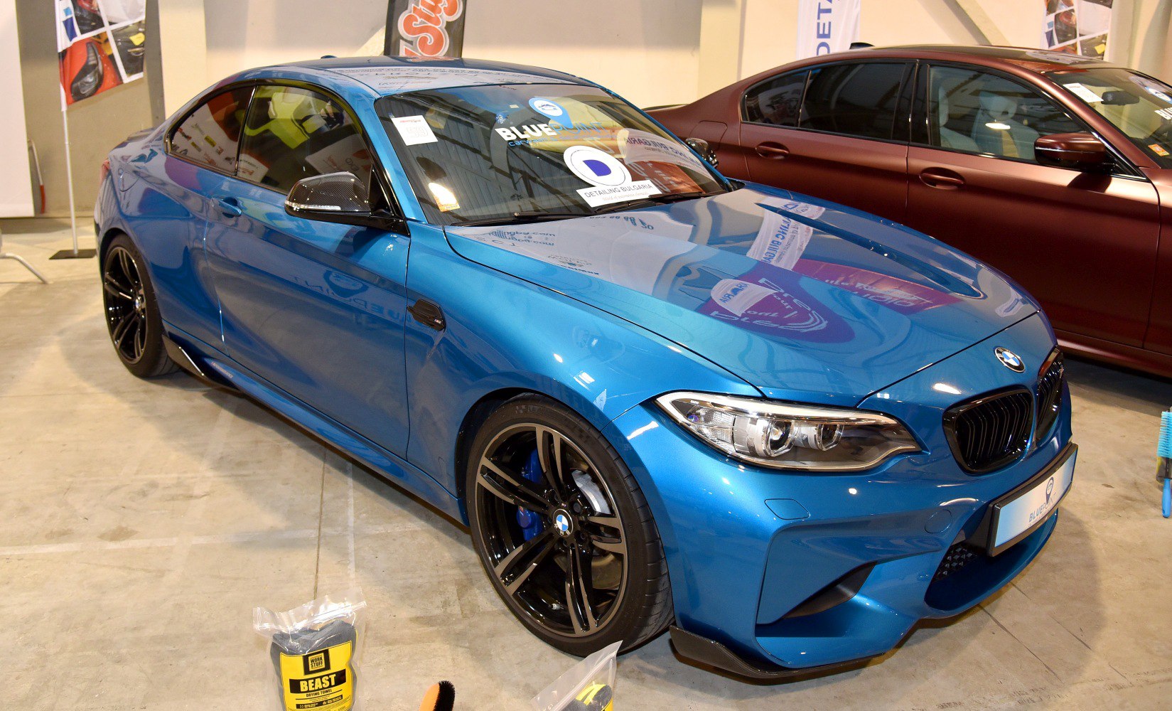 Blue metallic sporty coupe with black multi-spoke wheels and detailed front side profile.