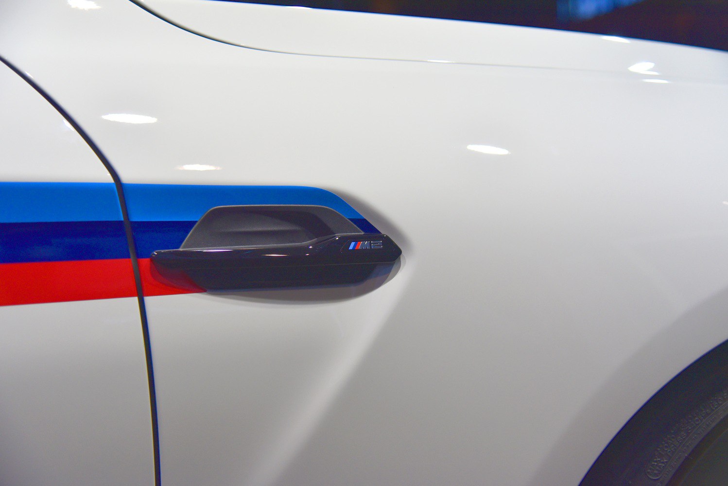 Black side vent with M logo and blue-red racing stripes on white car body