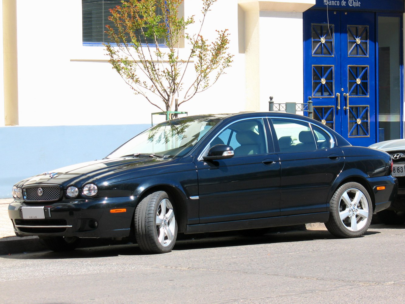 Black sedan with four doors and alloy wheels, side front angle