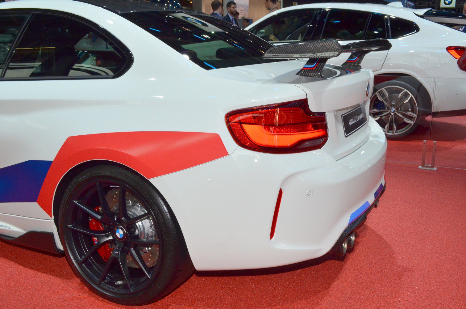 Carbon fiber rear wing and black multi-spoke wheels with red accents