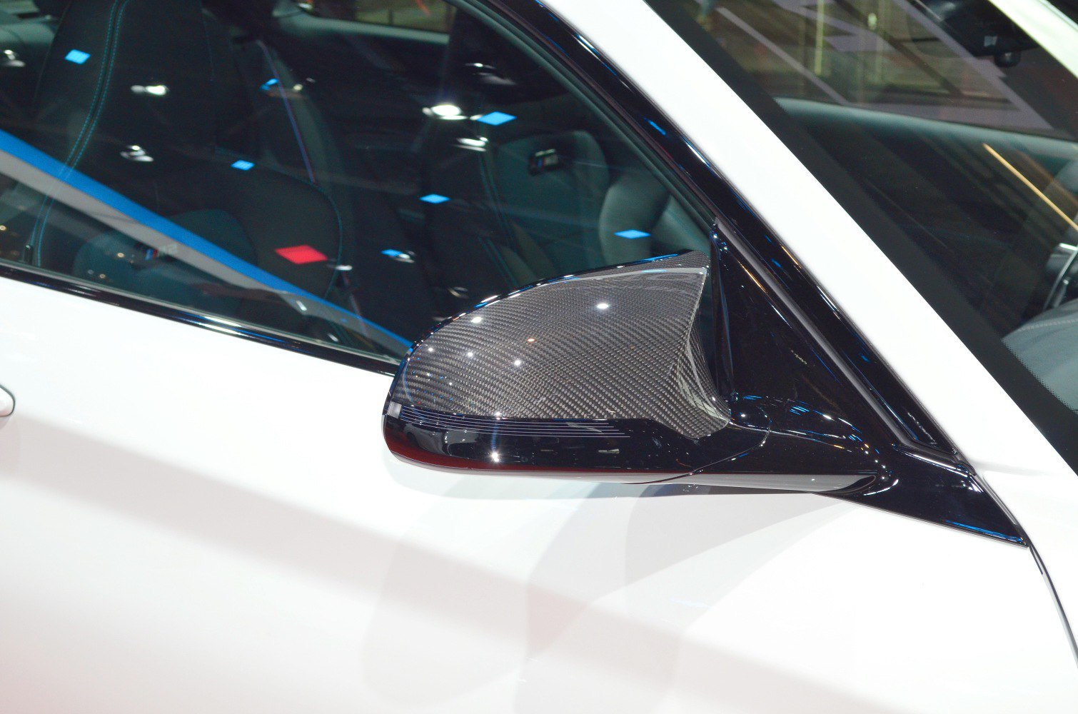 Carbon fiber side mirror close-up with black trim and reflections