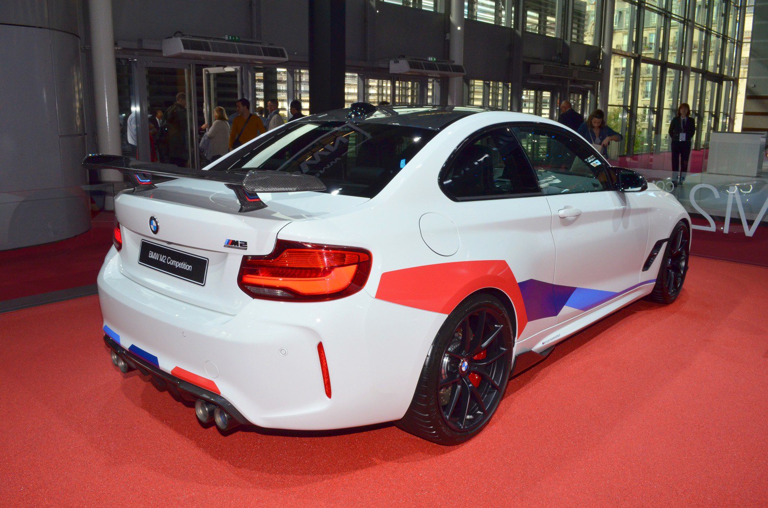 Rear three-quarter view with carbon fiber rear wing and quad exhausts