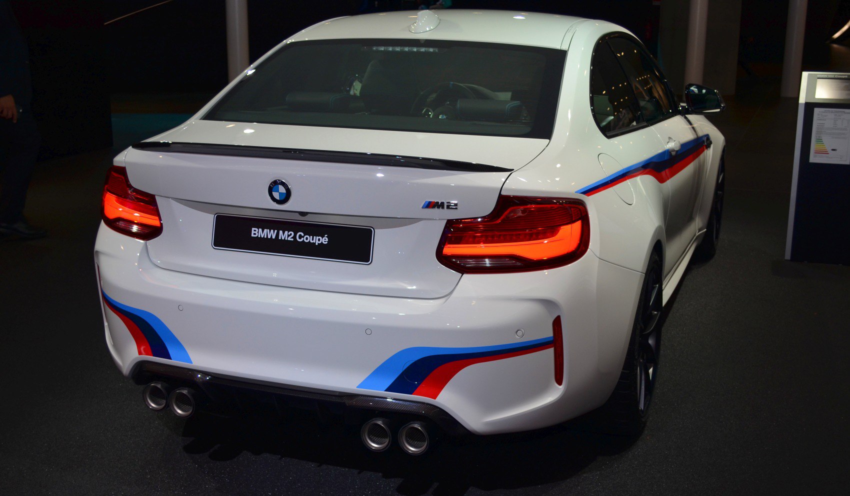 Rear view featuring quad exhaust, M stripes, and rear spoiler