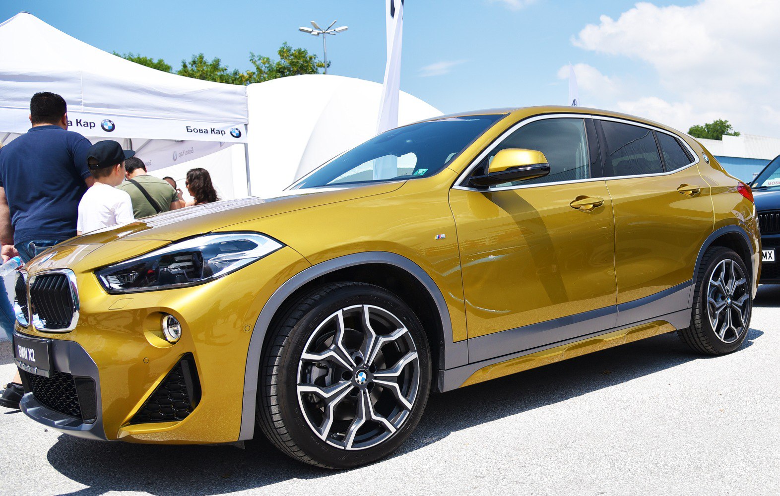 Front side view of a gold vehicle with M Sport wheels
