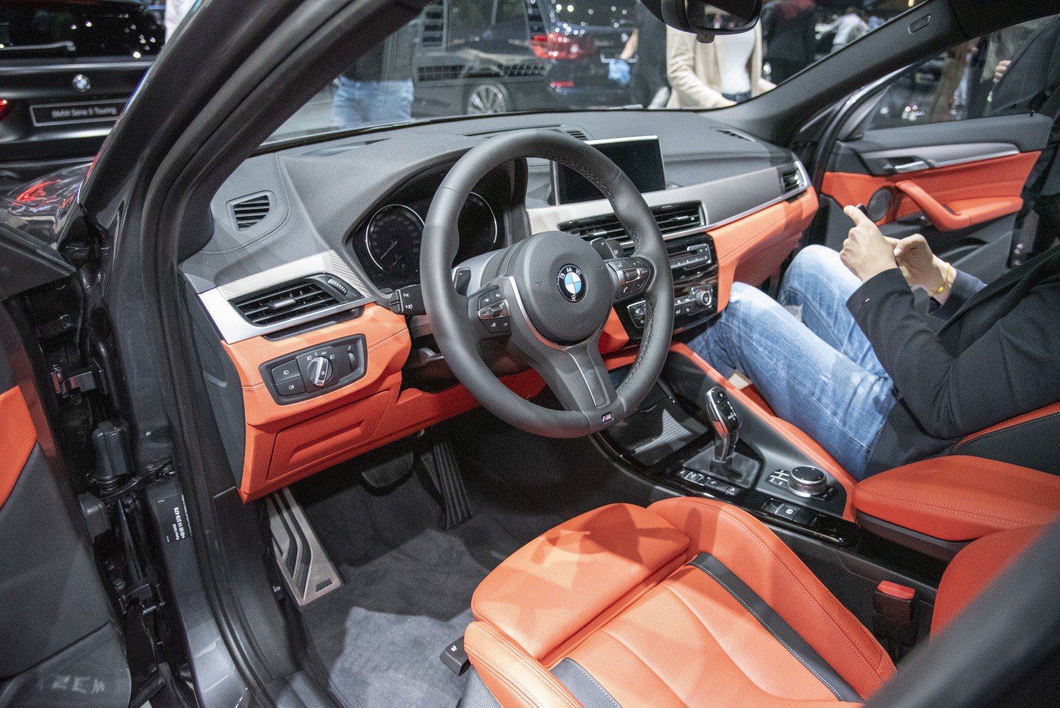 Sporty steering wheel and vibrant orange leather interior with dashboard controls