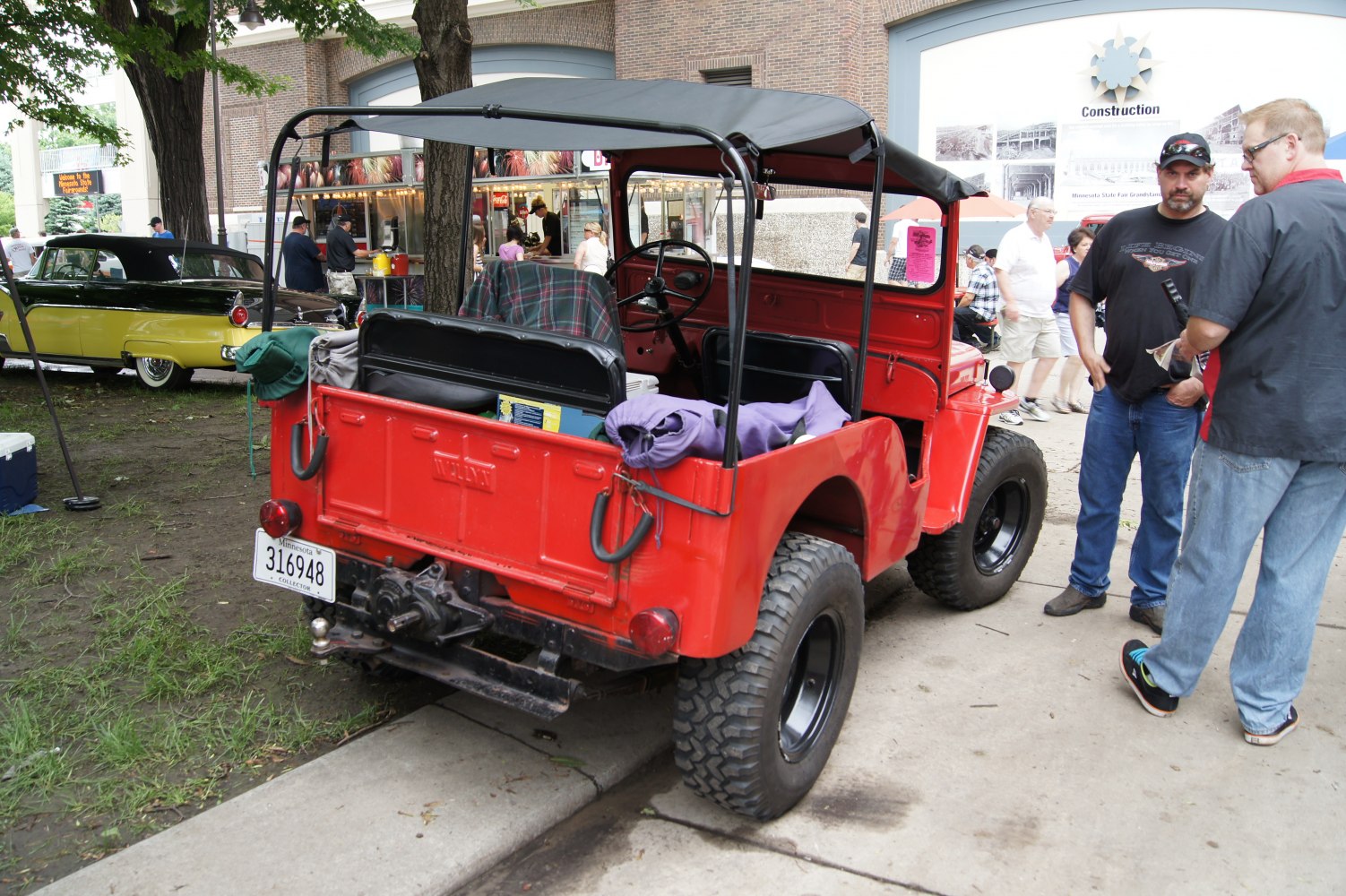 Red vintage off-road utility vehicle with black soft top and rugged tires
