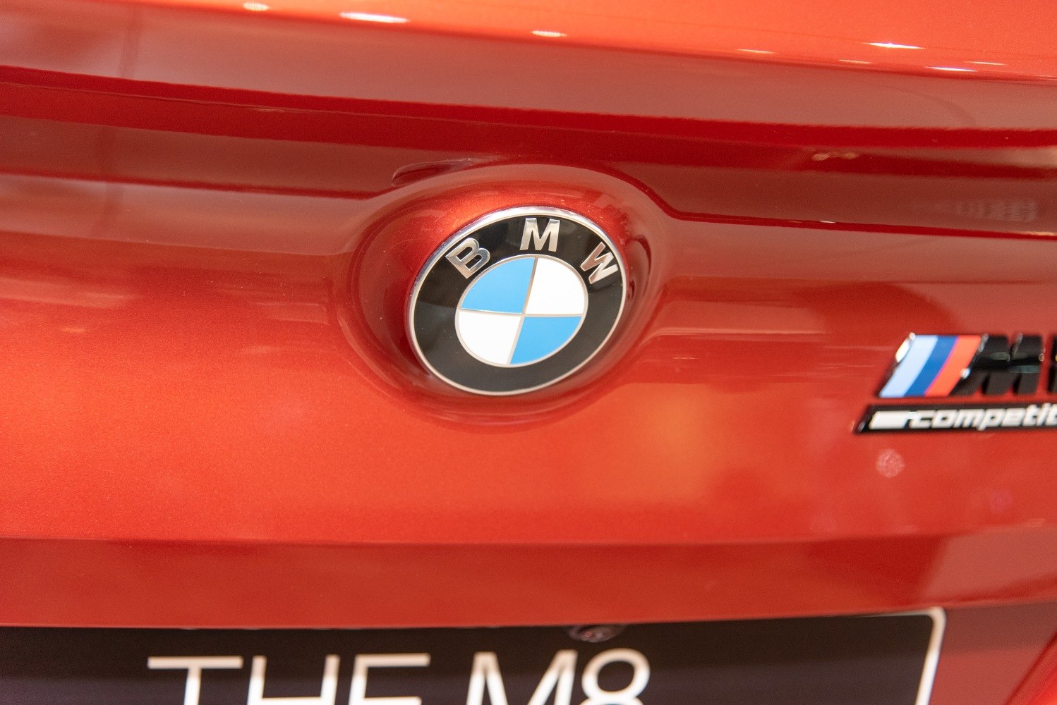 Close-up of rear BMW emblem and M competition badge on red car
