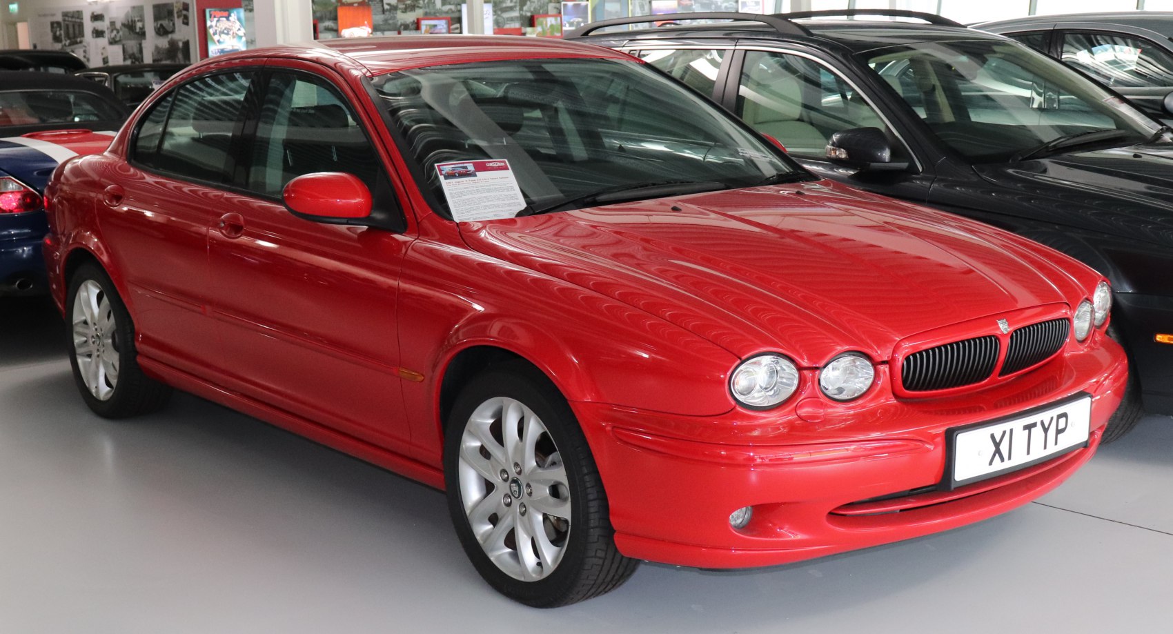 Red sedan with distinctive dual round headlights and classic grille.